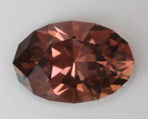 An Earth tone tourmaline oval, orange pink brown hue