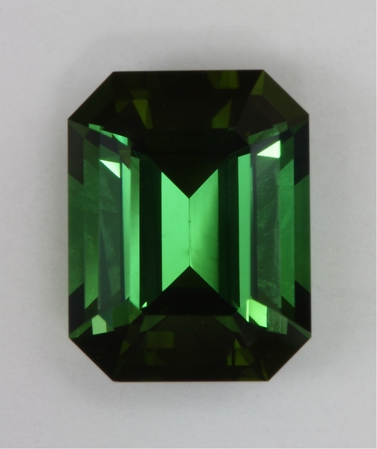 Medium toned green emerald cut with semi open ends.  #433