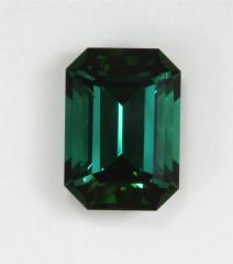 Dark toned emerald cut with flash driven blue green color.