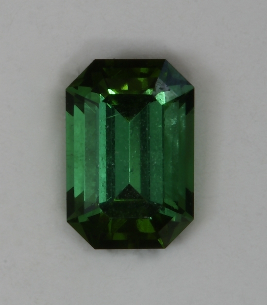 Well saturated green emerald cut with almost open ends.  #404